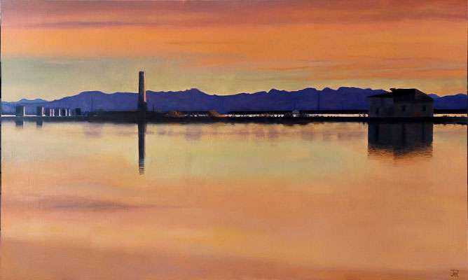 Atardecer en la Albufera con reflejos cálidos, montañas al fondo y estructuras tradicionales junto al agua.