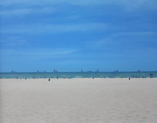 Playa de la Malvarrosa con bañistas, sombrillas y barcos en el horizonte vista desde el paseo marítimo.