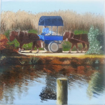 Carro azul tirado por dos caballos marrones junto a un canal, con reflejo en el agua y vegetación alta alrededor.