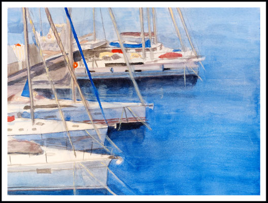 Veleros amarrados en el puerto de Valencia, reflejados en el agua tranquila bajo cielo claro.