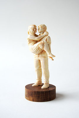 Das Paar (2015) 12cm. Das Bild zeigt einen Mann, der eine Frau in den Armen trägt. Die beiden schauen sich verliebt in die Augen. Die Bemalung der Figur wirkt wie Elfenbein.