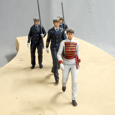 Miniaturpark "Die Kleine Sächsische Schweiz" Schifferumzug, 15cm. Das Bild zeigt eine kleine Prozession aus Miniaturen. Vornweg läuft eine Frau in weiß-roter Paradeuniform, gefolgt von blau gekleideten Kapitänen bzw. Seeleuten.