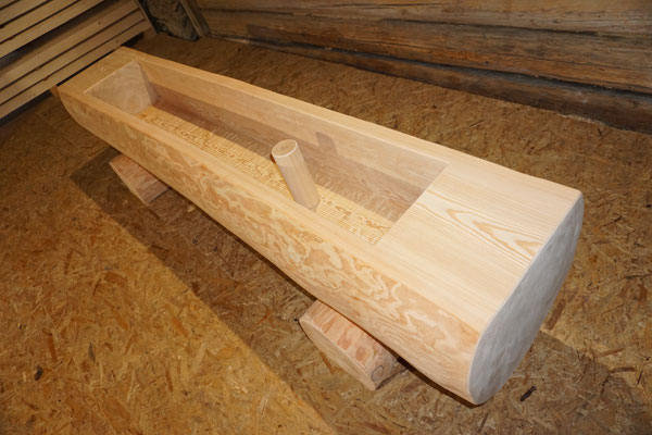 Detailansicht eines splintfreien Brunnentrogs aus Lärchen-Rundholz ohne Brunnenstock mit sichtbarem Innenbereich und Wasserablauf