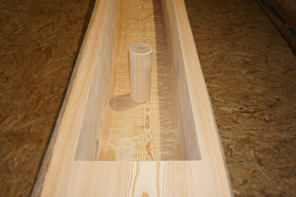 Detailansicht eines splintfreien Brunnentrogs aus Lärchen-Rundholz mit sichtbarem Standfuss und Holzstruktur