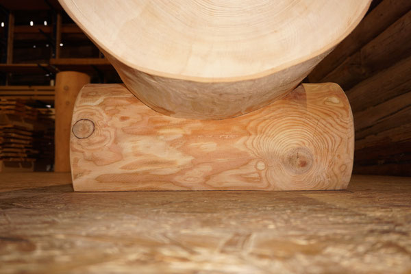 Detailansicht eines splintfreien Brunnentrogs aus Lärchen-Rundholz ohne Brunnenstock mit sichtbarer Fussauflage und Holzstruktur