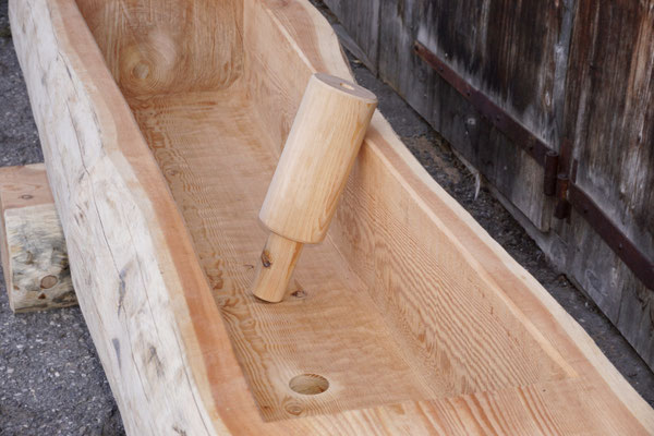 Detailansicht eines Brunnentrogs aus Lärchen-Rundholz mit Splint, sichtbare Innenbearbeitung mit Wasserauslauf und Ablauföffnung