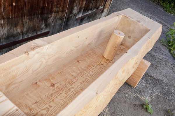 Detailansicht eines splintfreien Brunnentrogs aus Lärchen-Rundholz ohne Brunnenstock mit sichtbarem Innenbereich und Wasserablauf