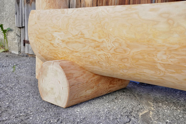 Detailansicht eines splintfreien Brunnentrogs aus Lärchen-Rundholz mit Brunnenstock, sichtbare Innenbearbeitung mit Wasserauslauf
