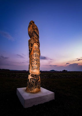 Eine aus Holz geschnitzte Eulenstatue am Abend