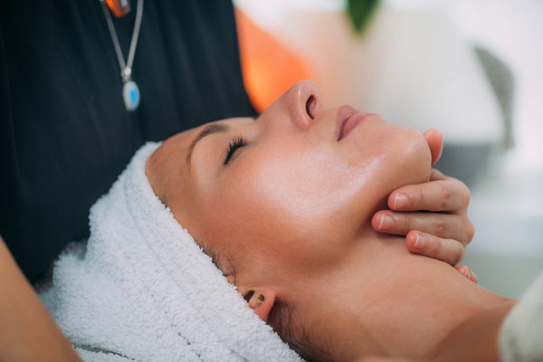 Frau erhält eine entspannende Gesichts- und Nackenmassage