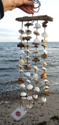 Windspiel in braun - natur im Seaside-Look. Naturdeko - Muschelwindspiel aus Herzmuscheln, Grasbällen und  dunkelbraunem Treibholz.