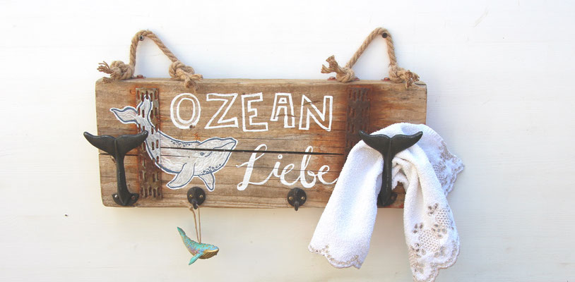 Massive Treibholzgarderobe mit handgelettertem Schriftzug "Ozean Liebe".