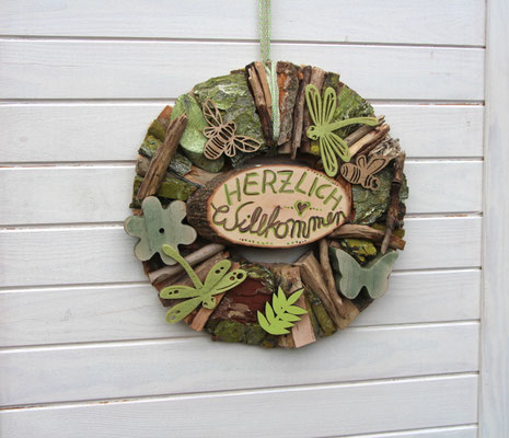 Holzkranz mit handgeschriebenem Holschild mit der Aufschrift "Herzlich Willkommen".