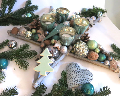 Detailansicht vom Tischstern mit vier Glasteelichtern: Graue Dekoaccessoires und dunkelgrüne Tanne passen prima zum Adventskranzstern
