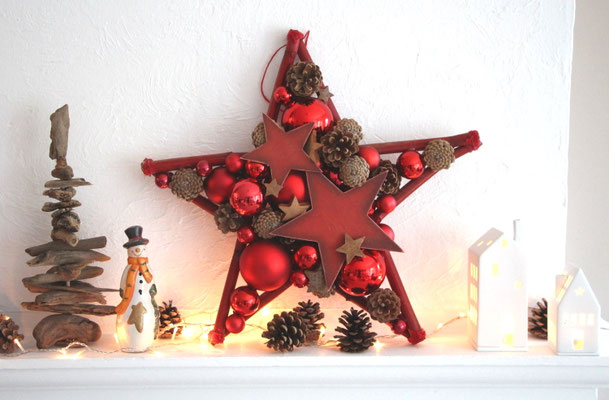 Deko Stern in klassischem Weihnachtsrot in 50 cm Größe aus roten Glaskugeln, Holzsternen und Nüssen. Aufgestellt auf einem Kaminsims in Kombination mit Zapfen und Weihnachtsmann.
