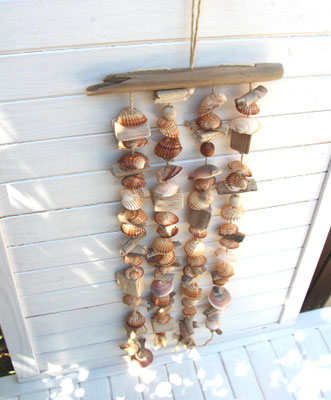 Die perfekte Sommerdeko: Hellbraunes Muschelwindspiel aus Treibholz, braun-weißen Muscheln, jede Muschel ist von Hand durchbohrt und aufgefädelt.
