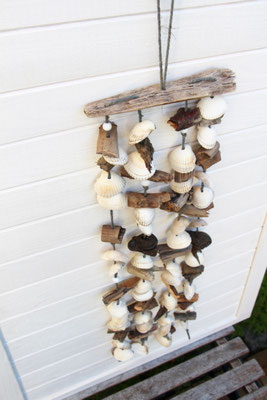 Weiße Muscheln ist abwechselnd mit Treibholz aufgefädelt und am Treibholzast befestigt.