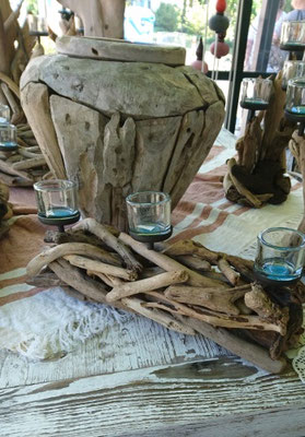 Vase und Holzbündel mit hellblauen Teelichtern aus blauem Glas