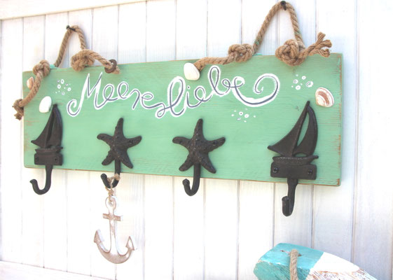 Maritime Wandgarderobe in meergrün mit dklbraunem, gusseisernen Seestern- und Segelboot Garderobenhaken. Mit handgeschriebenen"Meerliebe Schrifzug. Mit zwei Juteseilen als Aufhängung.