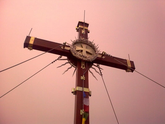Das Gipfelkreuz vor dem wolkigen Himmel.