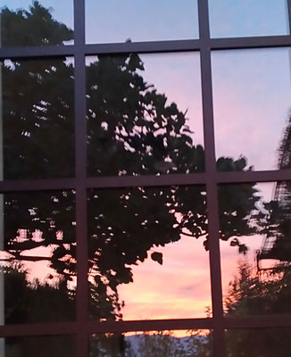 Mise en lumière d'une entrée. Création d'une porte de style atelier en acier. Vue de l'extérieur: reflet du lever de soleil sur la vitre.