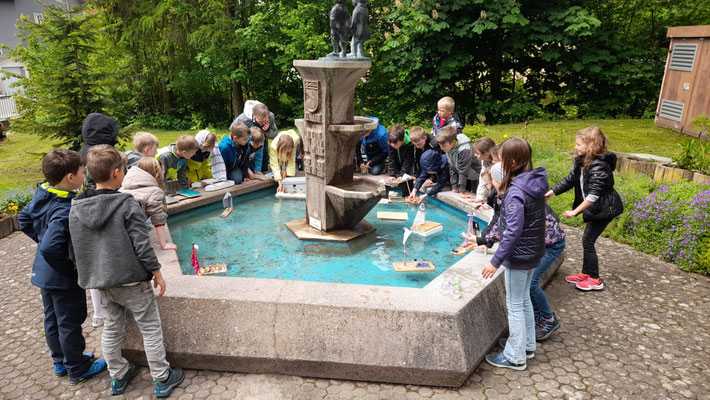 Kinder schauen die Boote im Brunnen an