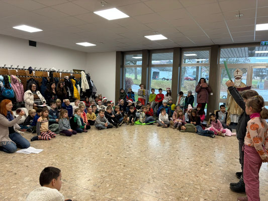 Die Kinder sitzen auf dem Boden, der Nikolaus steht an der Türe