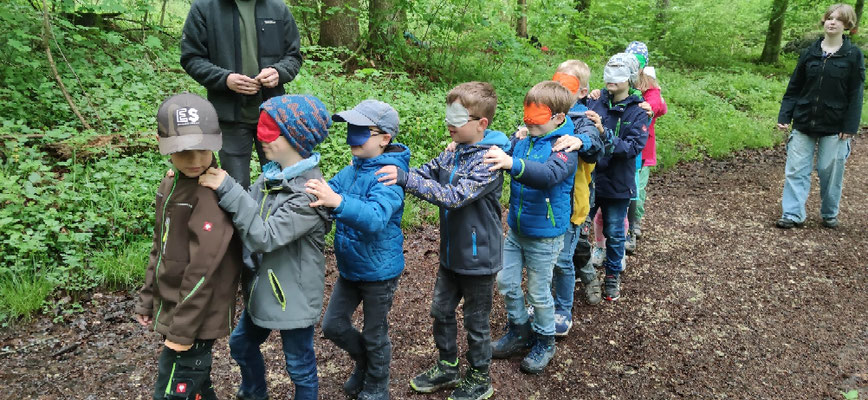 Ein Schüler führt seine Mitschüler die Augenbinden tragen