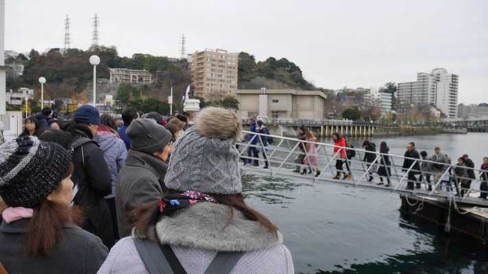 小雨降る中、多くの人が船を待ちます。