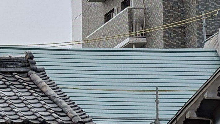 2025年1月28日（火）午後3時半　西大寺食堂前の空き地に立ちました。曇天に感じる岡山の晴れの空。風も強いです。こういう色に見えるのも、実は今回私たちの屋根に使われた緑色のガルバリウム鋼板なのです。朝の写真と印象が全く違います。どっちも綺麗。それが正直なところです。