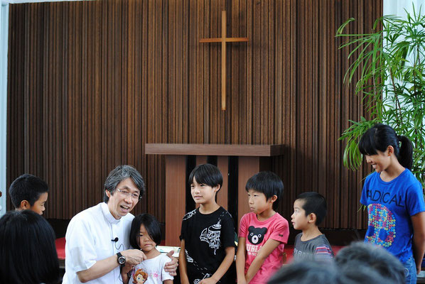 夏のファミリー礼拝の報告時に、森牧師は参加してくれた子どもたちにインタビュー中。お名前と学校と、いつも何して遊んでいるかな？