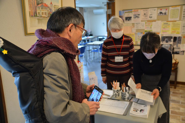 2024年2月4日（日）受付に名前を書かれる上島一高先生ですが、背中に背負っているのが小さいけれど大活躍のギターです。