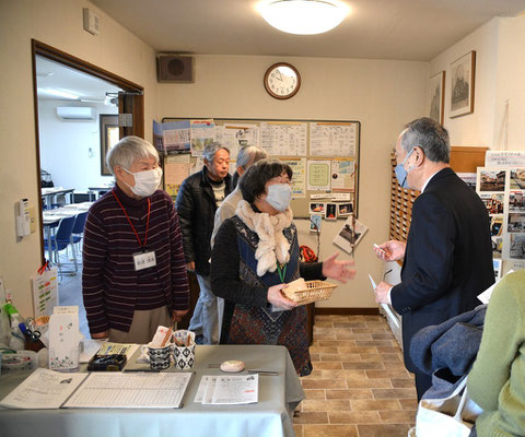 2025年1月26日（日）午前10時少し前。この日講師としてお迎えした橫野朝彦先生が到着。旭東教会名物・福音くじを引いて頂く場面です。説明する光代さんときよみさん。そして、後には十文字平和教会のはるおさんのお姿も。