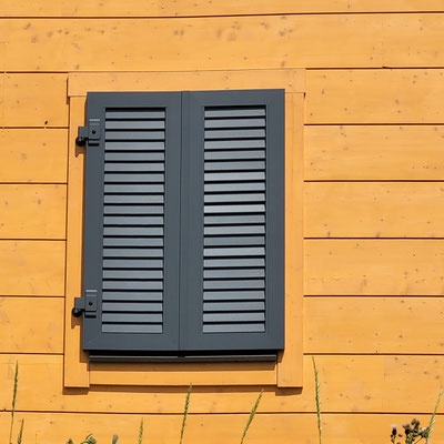 Wohnblockhaus mit Sichtschutz - Massivholzhaus mit Sonnenschutz - Klappläden 