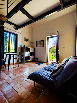 Un canapé confortable au rez-de-chaussée, donnant directement sur le jardin clos et arboré