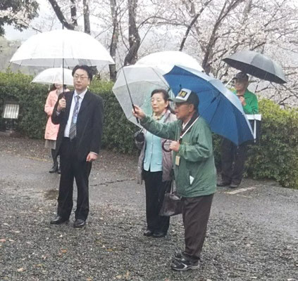 田原坂公園の慰霊碑前で、鱸（すずき）成久さん（写真左）と伴 和香子さん（中央）に説明する中尾会長