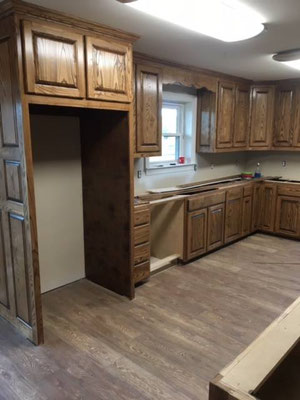 Cabinets done in Ash with "Chocolate" stain & lacquer finish. Refrigerator, Dishwasher, Sink area. Custom Valance over window connects upper cabinets beautifully