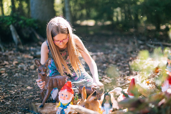 Mädchen spielt mit Zwergen im Wald am Biobauernhof Stadler