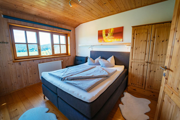 Schlafzimmer mit Boxspringbett und großem Fenster