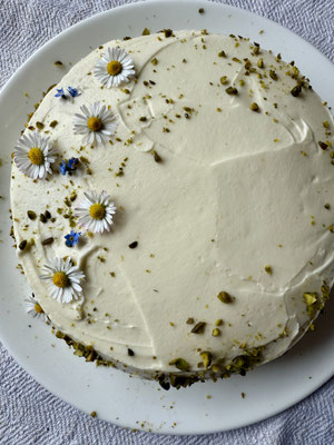 Mit Pistazienkernen und Gänseblümchen verziert – feiner Karottenkuchen im Frühling