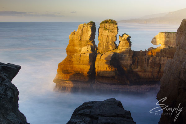 Punakaiki Pancake Rocks, Sonnenuntergang mit rötlich beleuchteten Felsen in der Meeresbrandung
