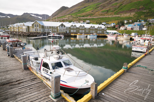 Boots-Steg mit einigen Booten und dem Hotel im Hintergung in Dalvík.