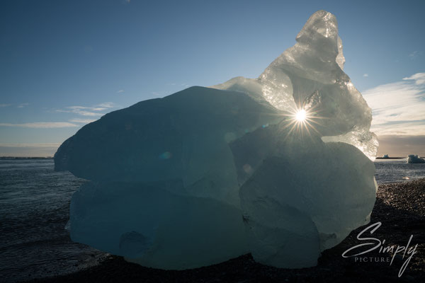 Grosse Eisscholle an der Jökulsárlón Glacier Lagoon mit der Sonne im Loch.