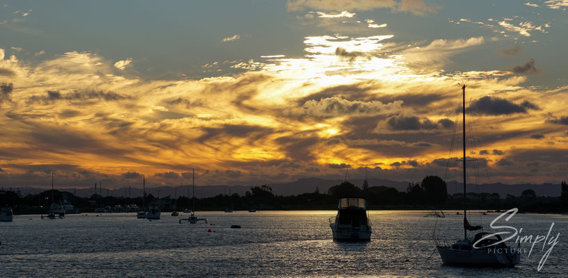 Whakatane, traumhafter Sonnenuntergang in der Hafenbucht mit gold-gelben Wolken