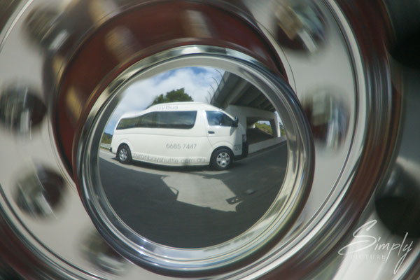 Queensland, Buss in einer Spiegelung auf einem Felgen eines vorbeifahenden Autos