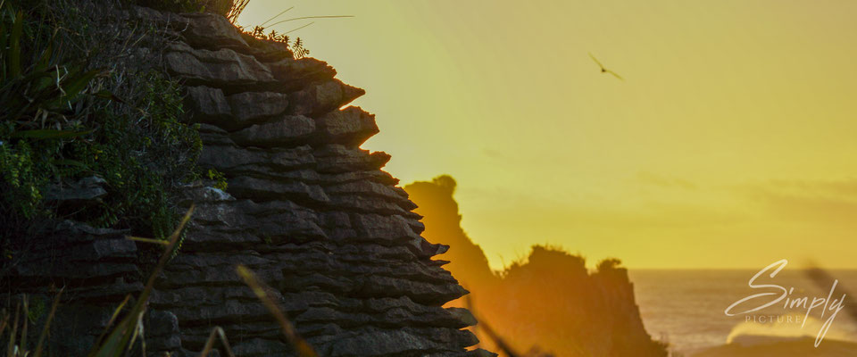Punakaiki Pancake Rocks, goldgelber Sonnenuntergang und das Profiel der Steinschichten im Vordergrund