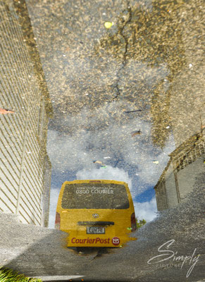 Russell, Reflektion eines Postauto's in einer Regenlache