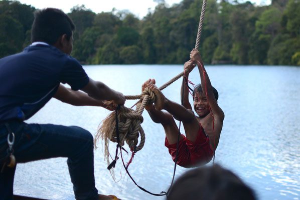 Local kids are having fun on the rope swing at the Yeak Laom Lake, Ratanakiri Province, Cambodia. It's a lovely summer's day to enjoy a swim in this beautiful clear crater lake. So much happiness and laughter is in the air!
