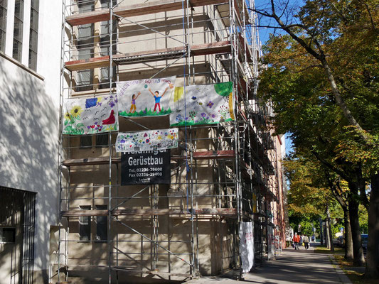 9.September: Jungschar hängt Banner am Gerüst auf und bringt Farbe ins Grau.