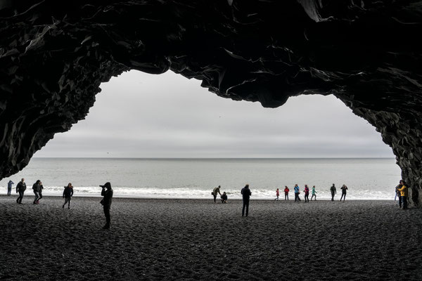 Iceland. Tourists visit a basalt cave on the black beach in Reynisfjara, one of the most picturesque places on the island.